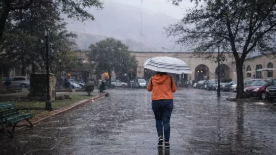 Mujer atravesando una plaza con paraguas bajo la lluvia