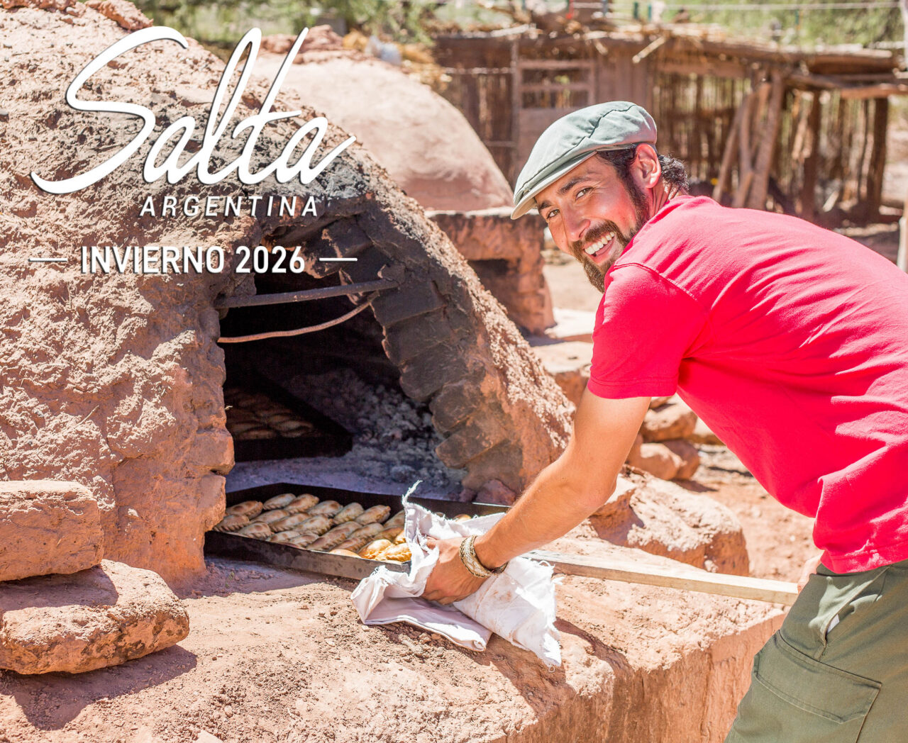 Hombre sacando empanadas del horno de barro